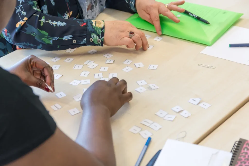 ESOL learners arranging English vocabulary flashcards together at a classroom table