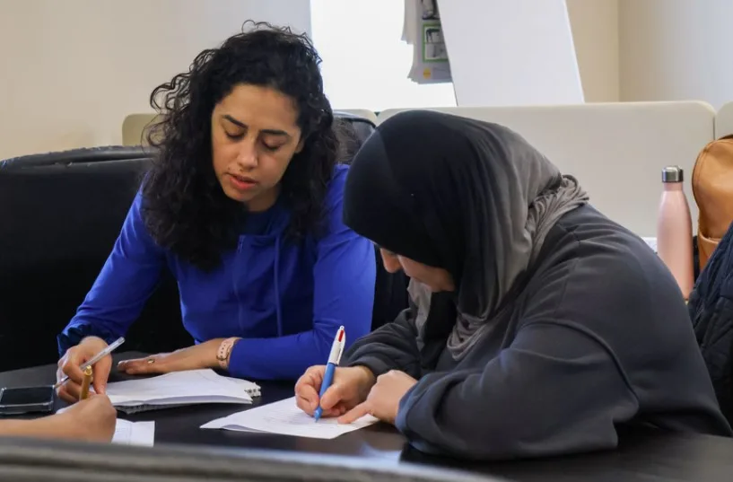 One learner gently helping another to write, showing peer support during class