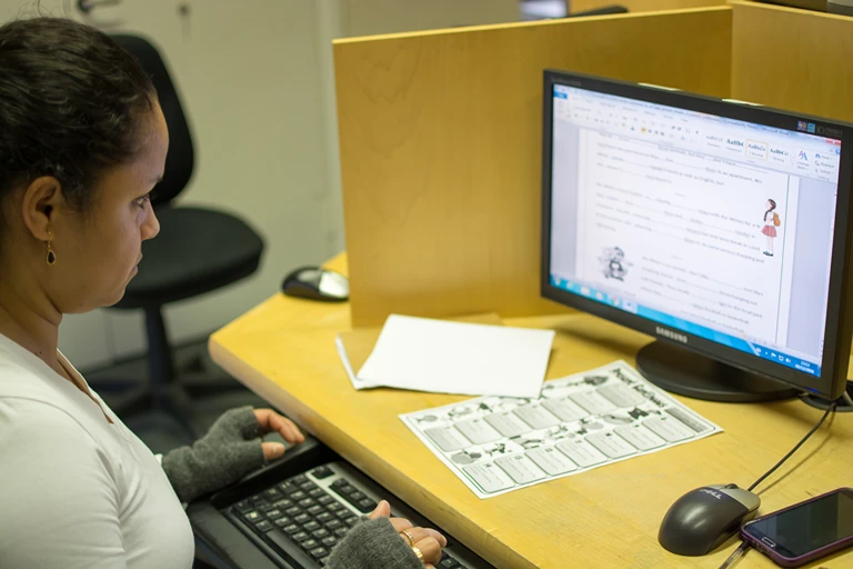 An adult learner practising digital skills on a computer, working in a word processor at a workstation