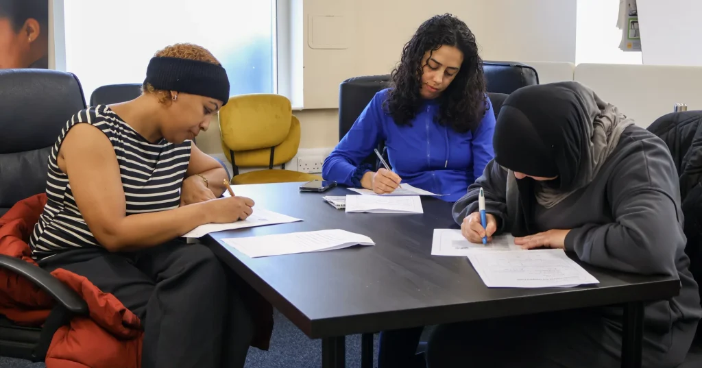 Three learners filling in enrolment forms around a table