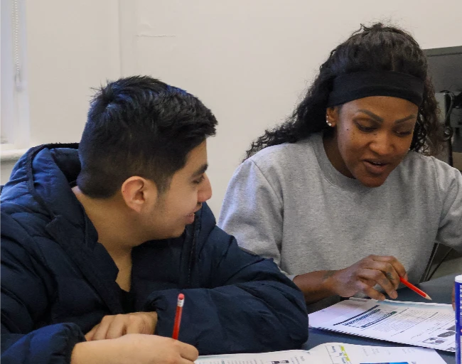 Two young adult learners sitting side by side working through their coursework together